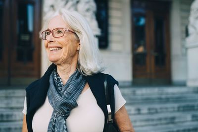 Smiling senior woman looking away while exploring city
