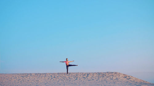 Healthy, young beautiful woman meditating, stretching, practicing yoga on the sea beach, at sunrise