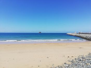 Scenic view of beach against clear blue sky