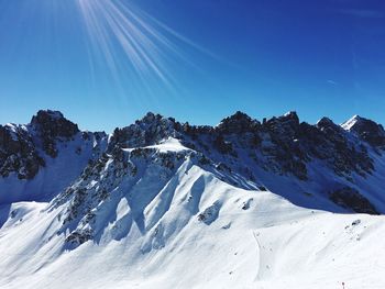 Scenic view of snowcapped mountains against blue sky