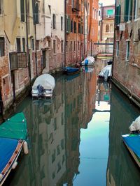 Boats moored in canal amidst buildings in city