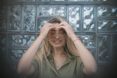 Woman adjusting hair against glass wall