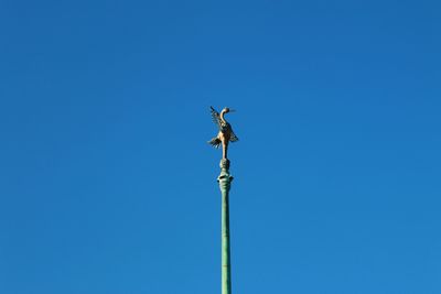 Low angle view of weather vane against clear blue sky