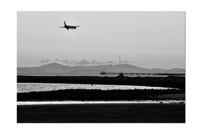 Airplane flying over land against sky