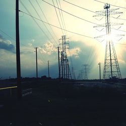 Electricity pylon against cloudy sky