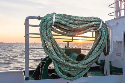 Close-up of fishing net in sea against sky during sunset