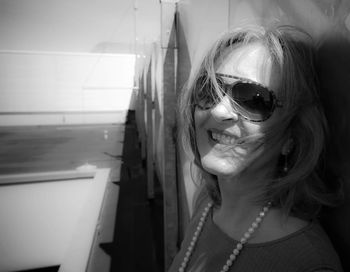 Close-up portrait of senior woman wearing sunglasses against wall