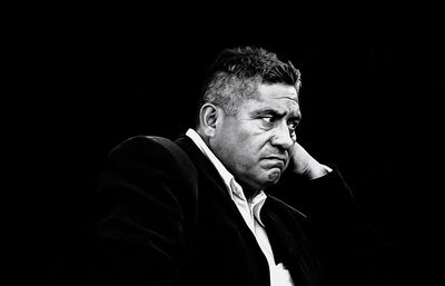 Portrait of young man looking away against black background