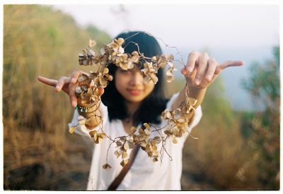 Portrait of smiling teenage girl showing dry leaves wreath