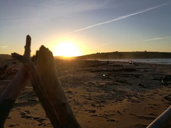 Close-up of hand on beach against sky during sunset