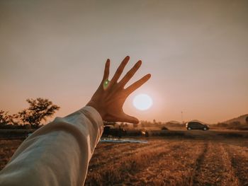 Midsection of person on field against sky during sunset