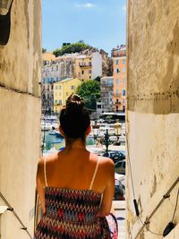 Rear view of woman standing against buildings in city