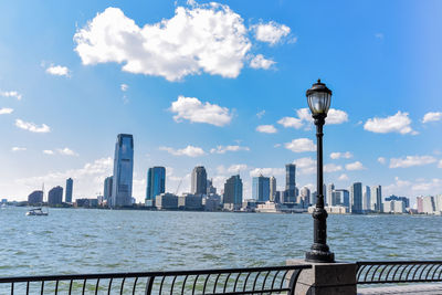 New jersey skyline from battery park in a sunny day. cityscape view through trees and streetlamp.nyc
