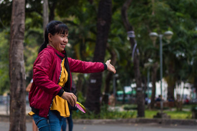 Side view of smiling girl standing against trees