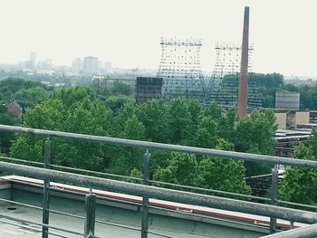 Trees and cityscape against sky