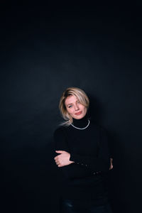 Portrait of woman standing against black background