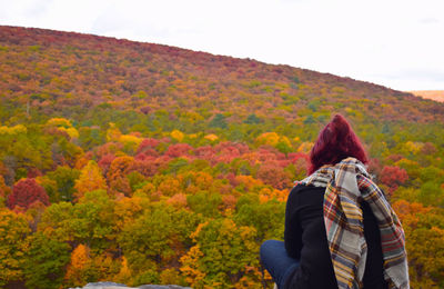 Rear view of woman looking at trees on mountain against sky during autumn