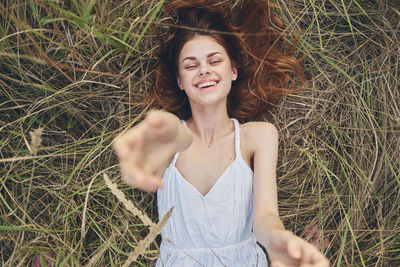 Young woman smiling while standing against grass