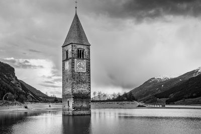 Abandoned tower amidst lake against cloudy sky