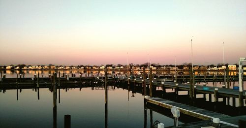 Boats moored in harbor at sunset