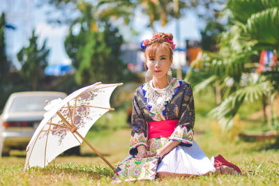 Young woman with umbrella against plants