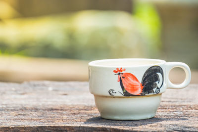 Coffee cup with chicken painting in ancient chinese style, on the old wood table, natural light.