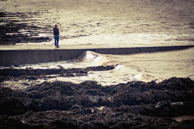 Man standing on rock at beach