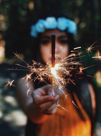 Close-up of woman holding sparkler at night