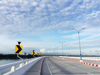 Road sign on bridge against sky