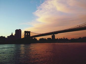 Suspension bridge over river at sunset