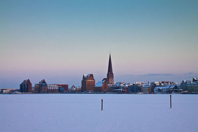 City at waterfront against clear sky