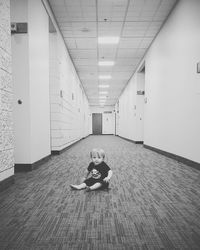 Boy sitting on floor in corridor