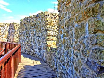 Stone wall by water against sky