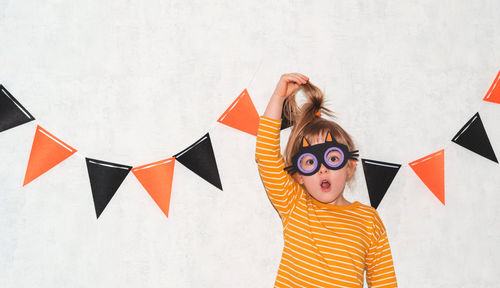 Portrait of a child in a cat mask.the girl holds her hair by the ponytail.halloween holiday concept.