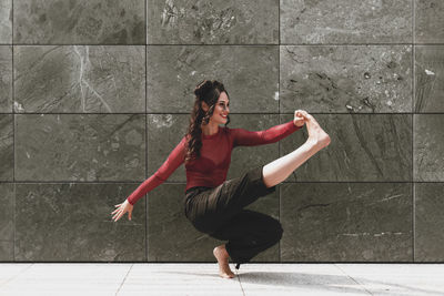 Full length of woman dancing on floor against wall