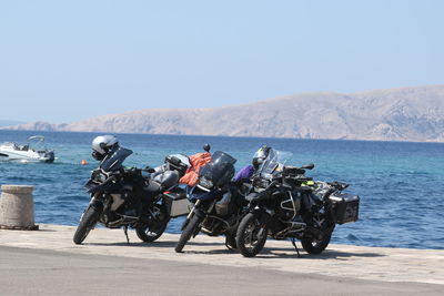 Motorcycles by sea against clear sky