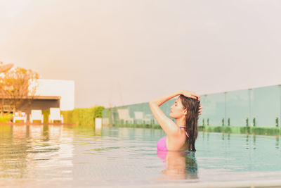 Side view of woman swimming in pool against clear sky