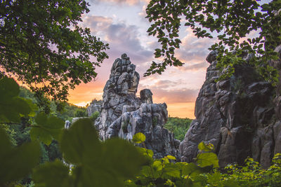 Low angle view of rock formation amidst trees against sky