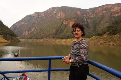 Portrait of woman standing by railing against mountains