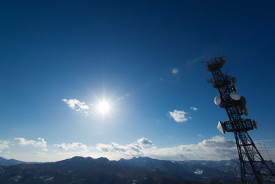 Low angle view of communications tower by mountain against sky