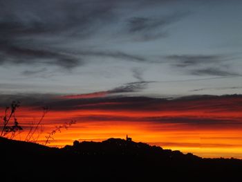 Silhouette landscape against dramatic sky during sunset