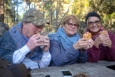 Smiling senior people eating food sitting outdoors