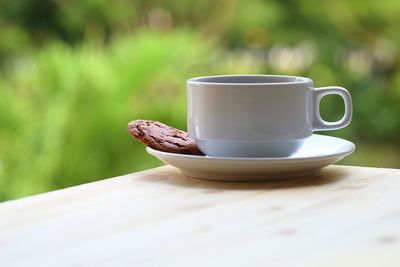 Close-up of coffee cup with cookie on table