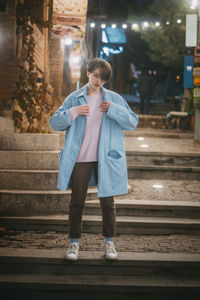 Full length portrait of teenage girl standing at night