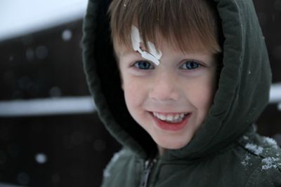 Close-up portrait of smiling boy in warm clothing during winter
