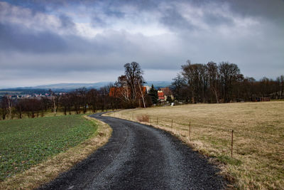 Road amidst field against sky