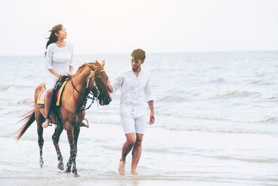 Full length of people riding on beach against sky