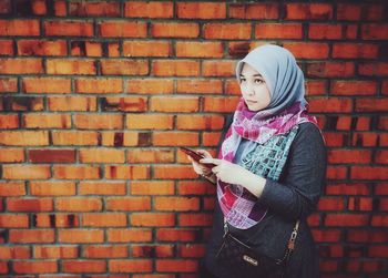 Full length of woman standing against brick wall