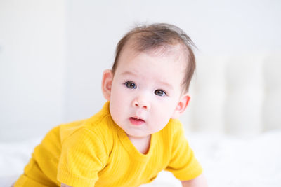 Portrait of cute baby boy looking away against white background