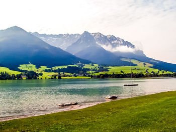 Scenic view of lake by mountains against sky